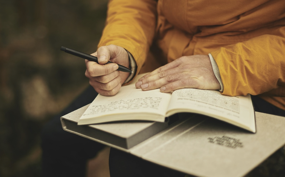 Close-up of a Hand Writing in a Notebook in an Outdoor Setting