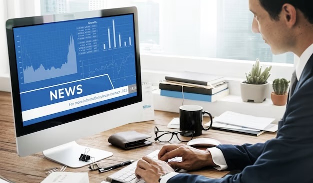 A man works at a computer with the inscription news